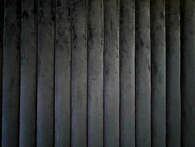 Industrial interior wall panels clad in dark rexine material with a matte finish and fine grain.