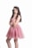 A young woman with long, wavy hair is wearing a sparkling pink dress and a jeweled tiara. She is standing with one hand on her waist and the other resting near her chin, exuding elegance.