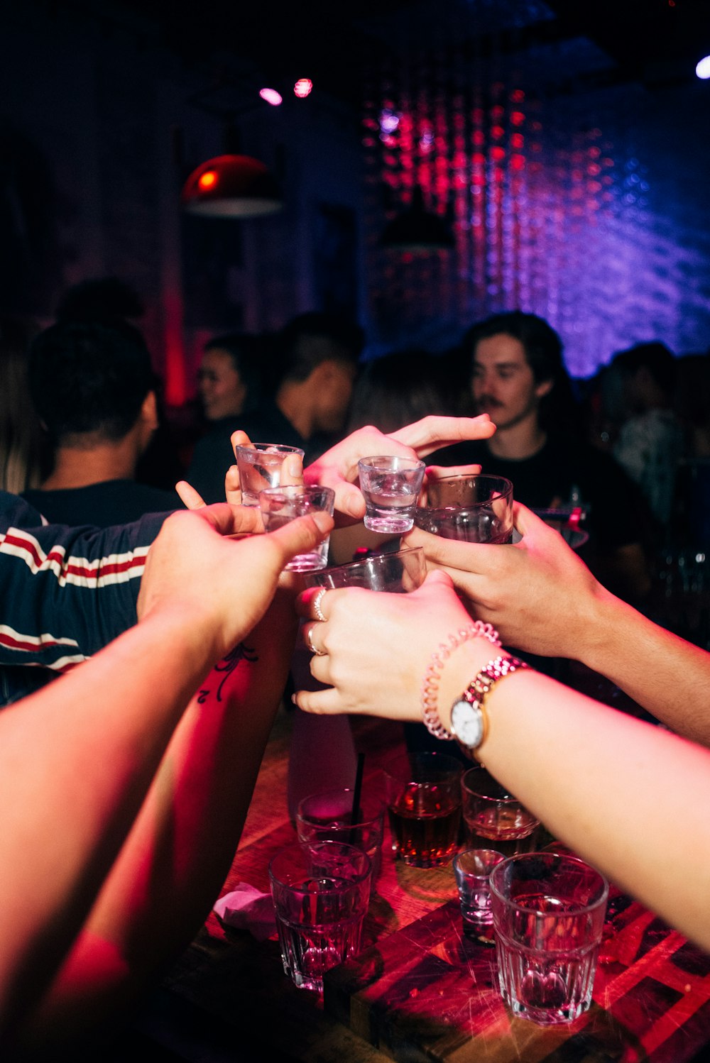 a group of people reaching for drinks at a bar