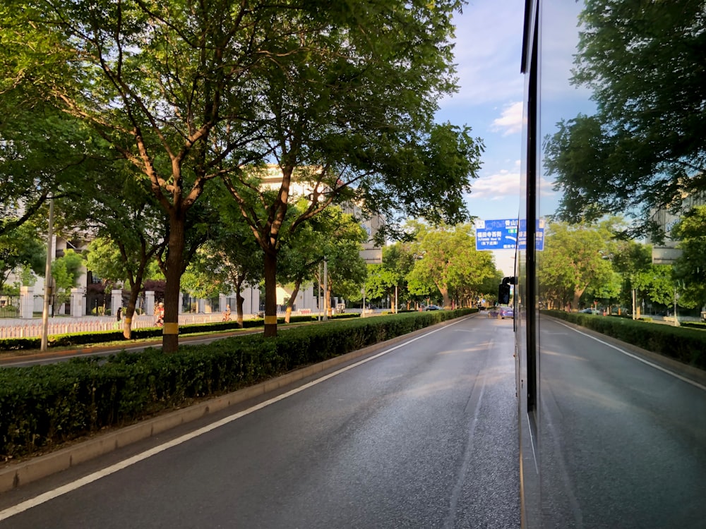 a street lined with trees and bushes next to a street sign