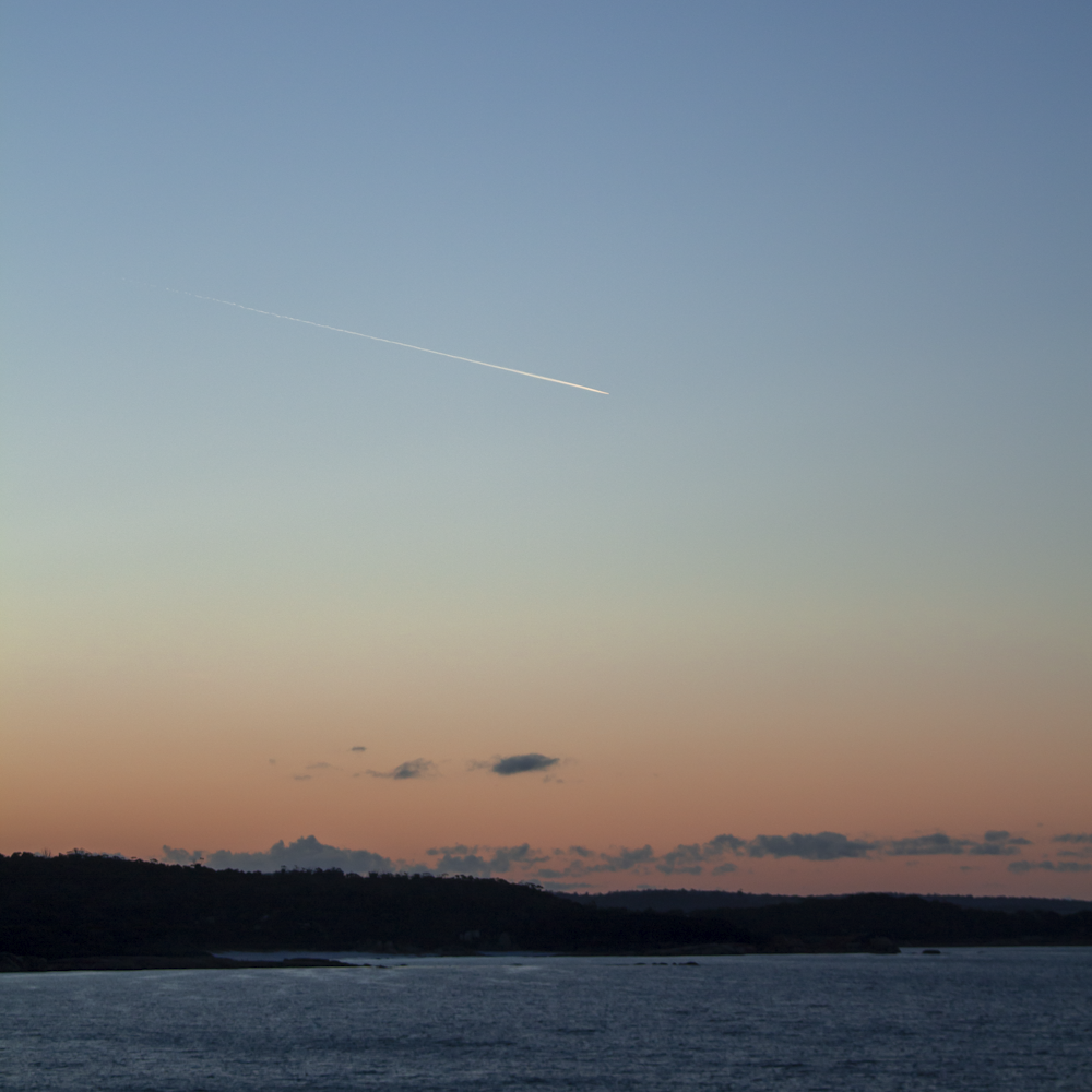 a plane flying in the sky over a body of water