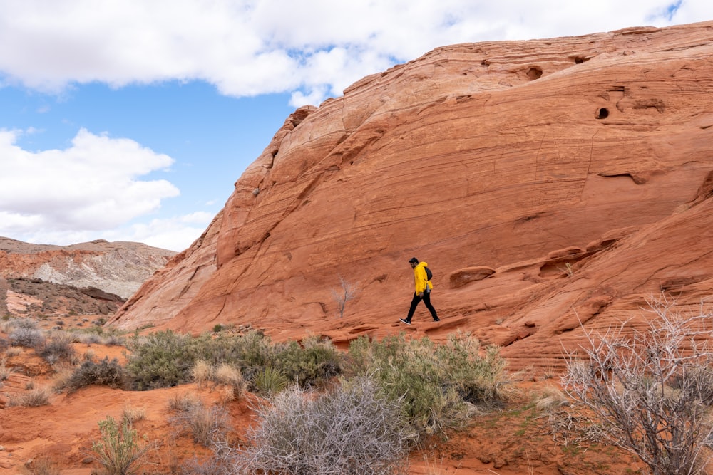 a man in a yellow jacket is walking in the desert