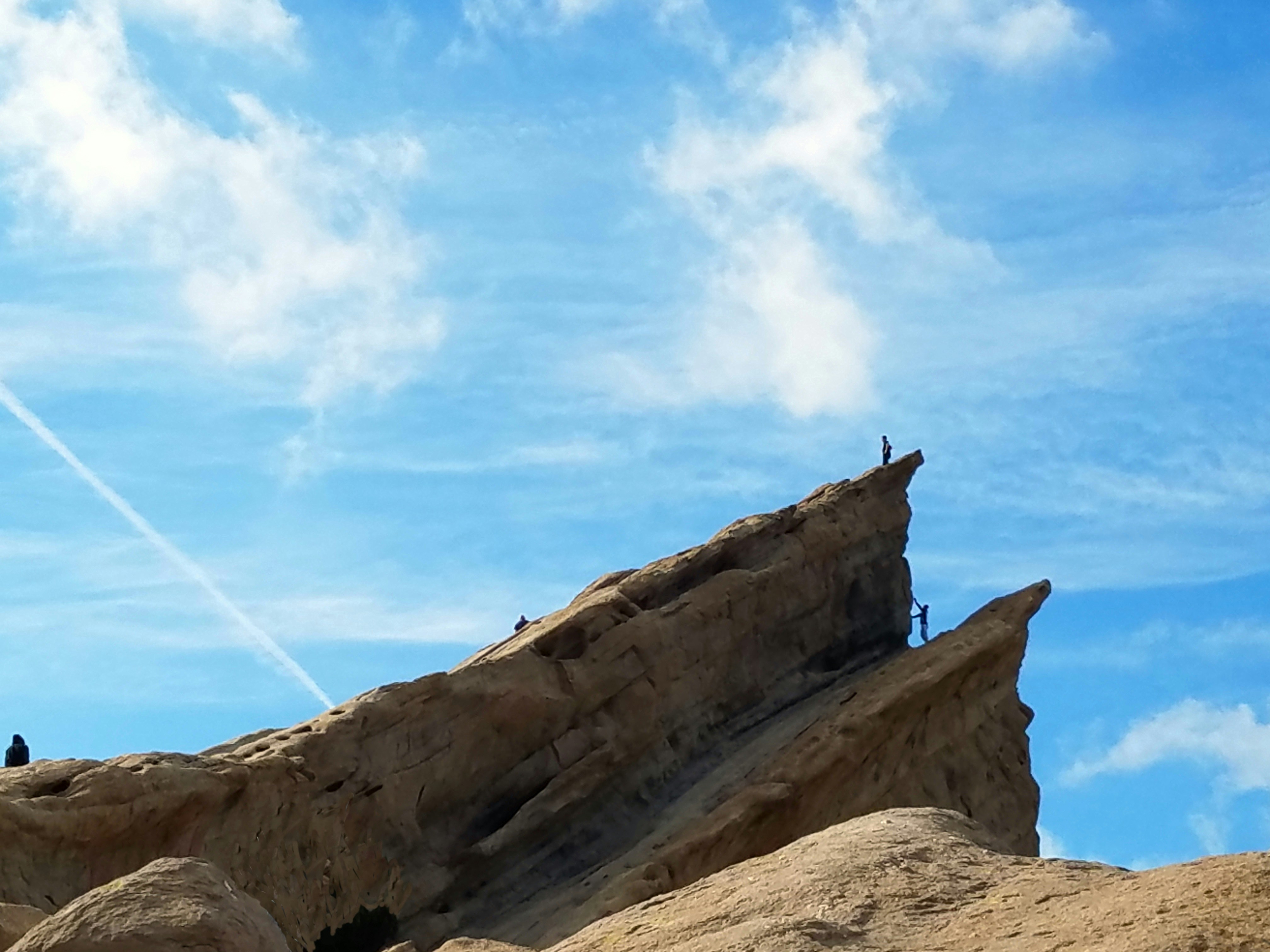 a group of people standing on top of a large rock, 