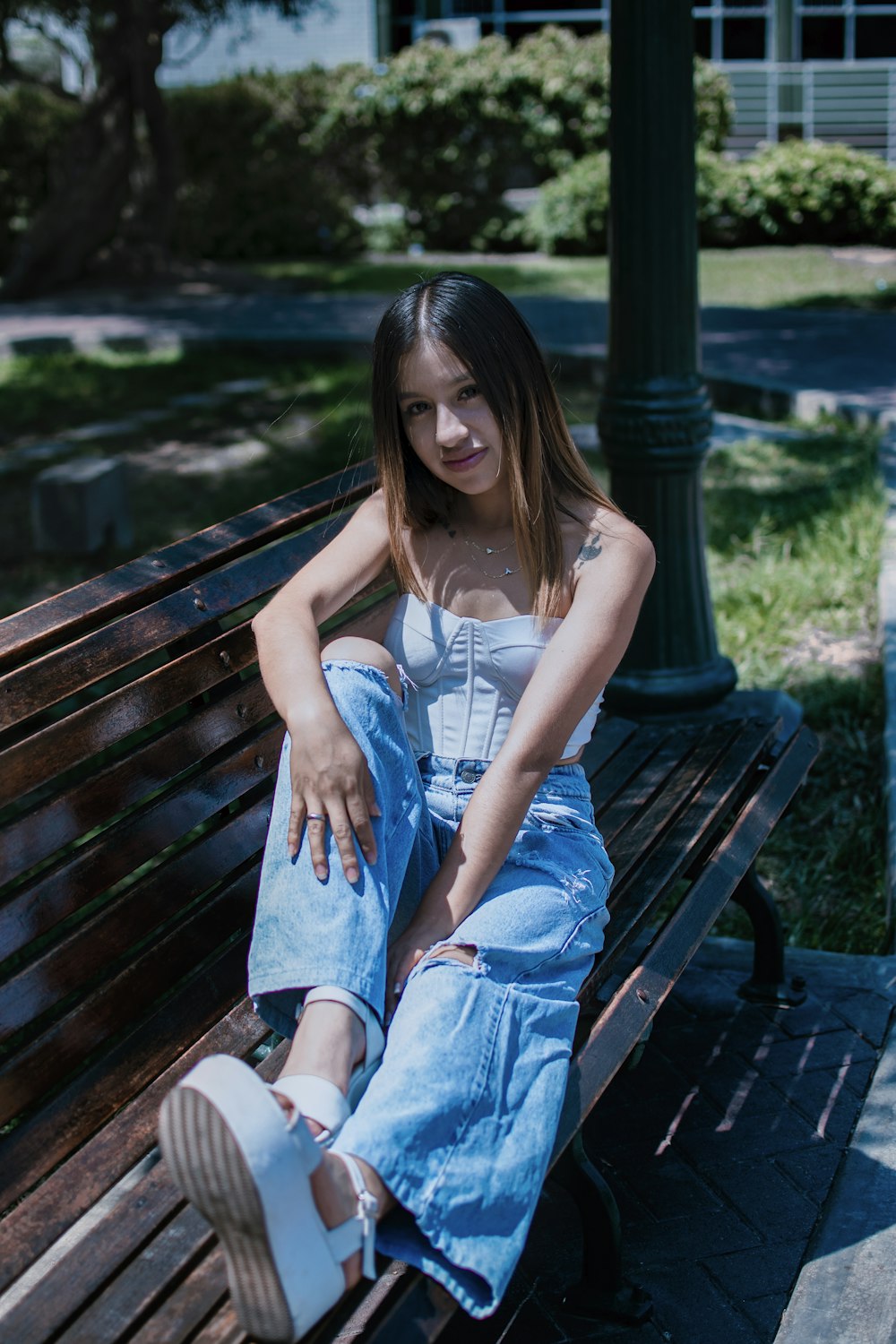 a woman sitting on a wooden bench in a park