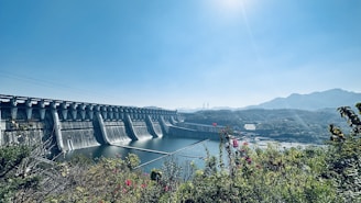 Hydroelectric dam with water flowing energetically beneath a sunny sky