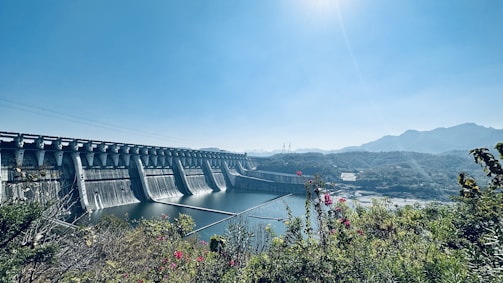 Hydroelectric dam with water flowing energetically beneath a sunny sky