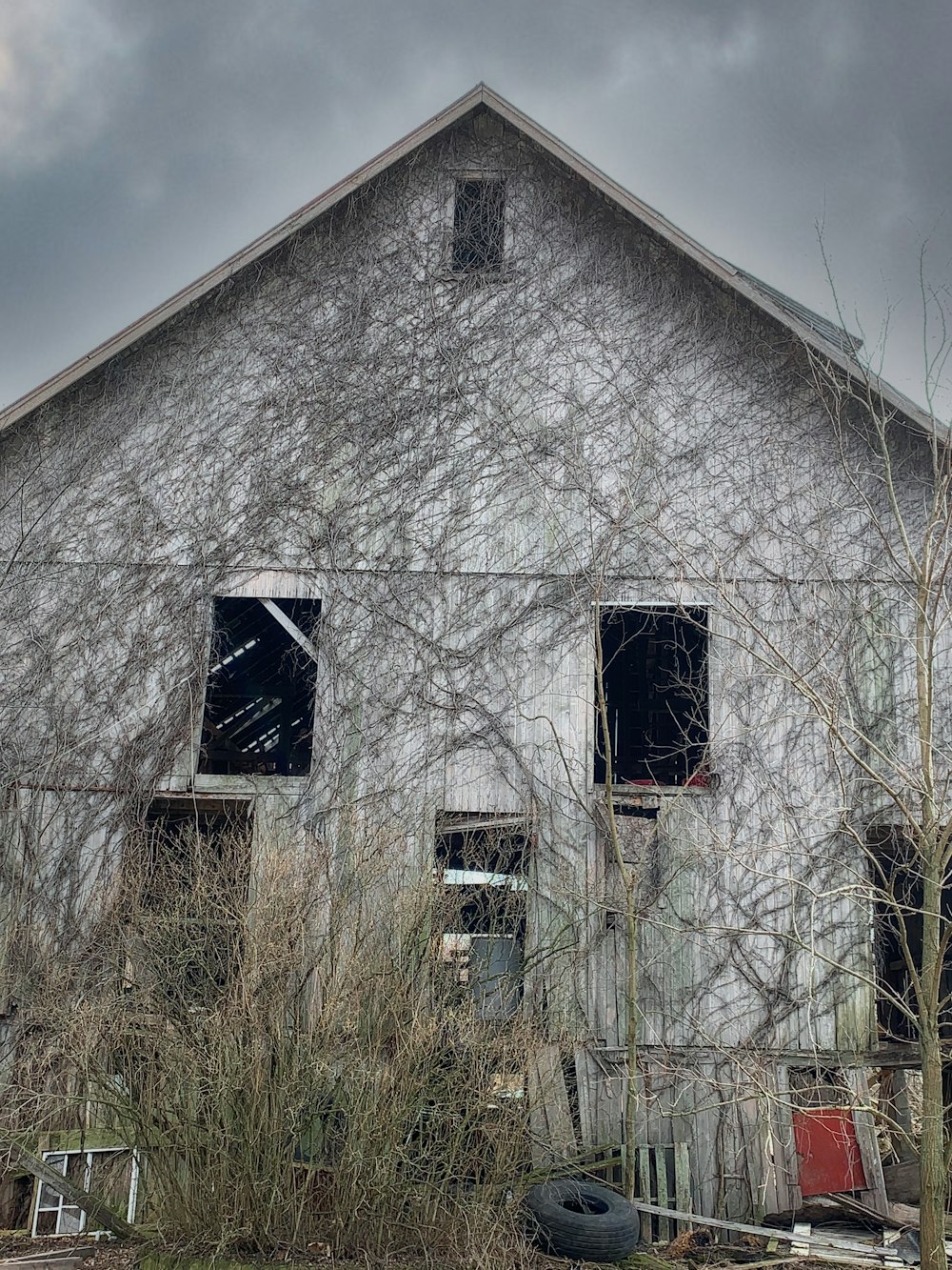 an old barn with broken windows and vines growing on it