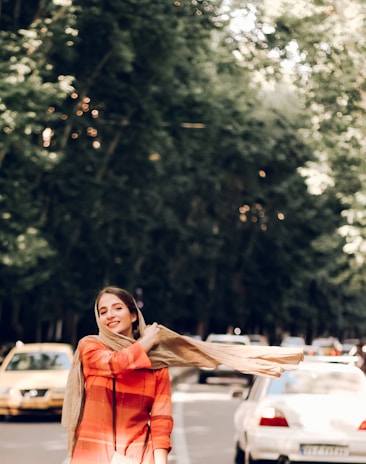 Smiling woman wearing a classic solid color scarf while enjoying a brisk outdoor walk.