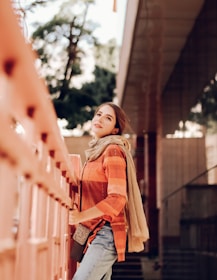 Attractive woman in a relaxed pose, wearing casual clothes with subtle orange highlights.