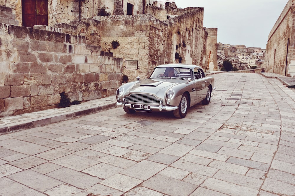 an old car parked on a cobblestone street