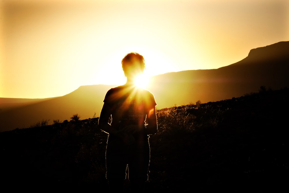 a person standing on a hill at sunset