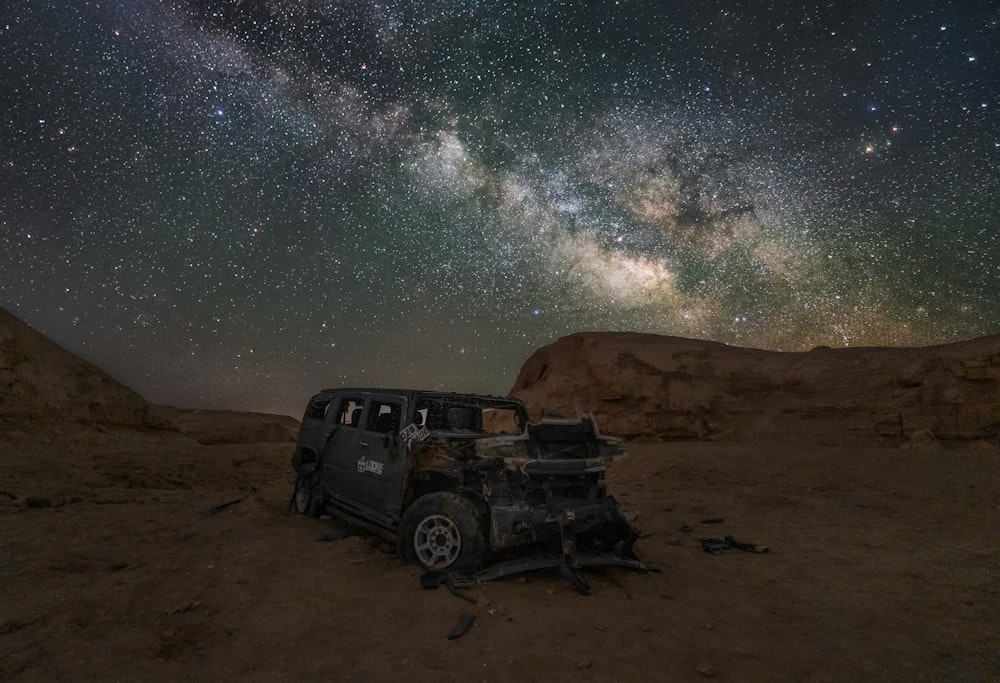 a jeep parked in the middle of a desert under a night sky filled with stars