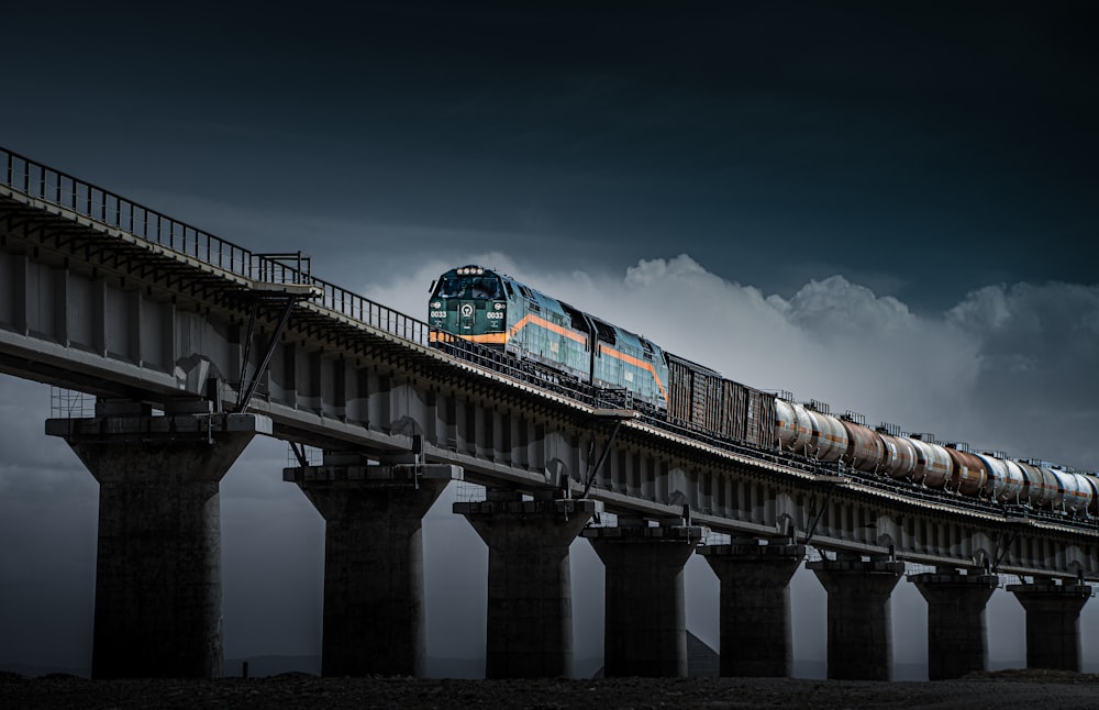 a train traveling over a bridge under a cloudy sky