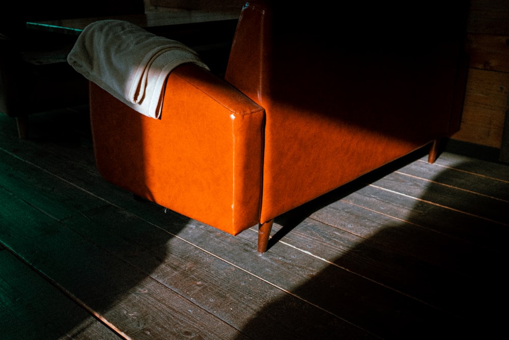 uma cadeira laranja sentada em cima de um piso de madeira