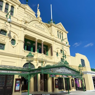 A historic theater building with ornate architectural details, featuring columns, decorative molding, and arched windows. The facade is painted in a light yellow color with green accents. The sign reads 'Gaiety Theatre' and a banner advertises a performance of 'Once'.