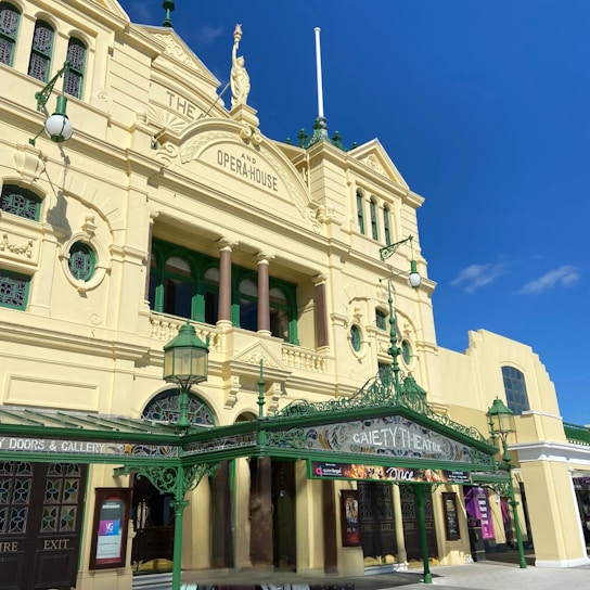 A historic theater building with ornate architectural details, featuring columns, decorative molding, and arched windows. The facade is painted in a light yellow color with green accents. The sign reads 'Gaiety Theatre' and a banner advertises a performance of 'Once'.