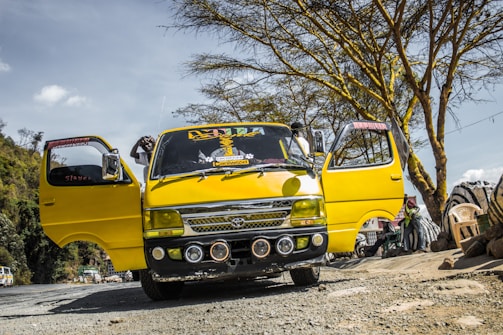 A comfortable minibus parked by a scenic countryside road during a sunny day.