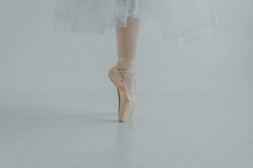 a ballerina in a white tutu and pink ballet shoes