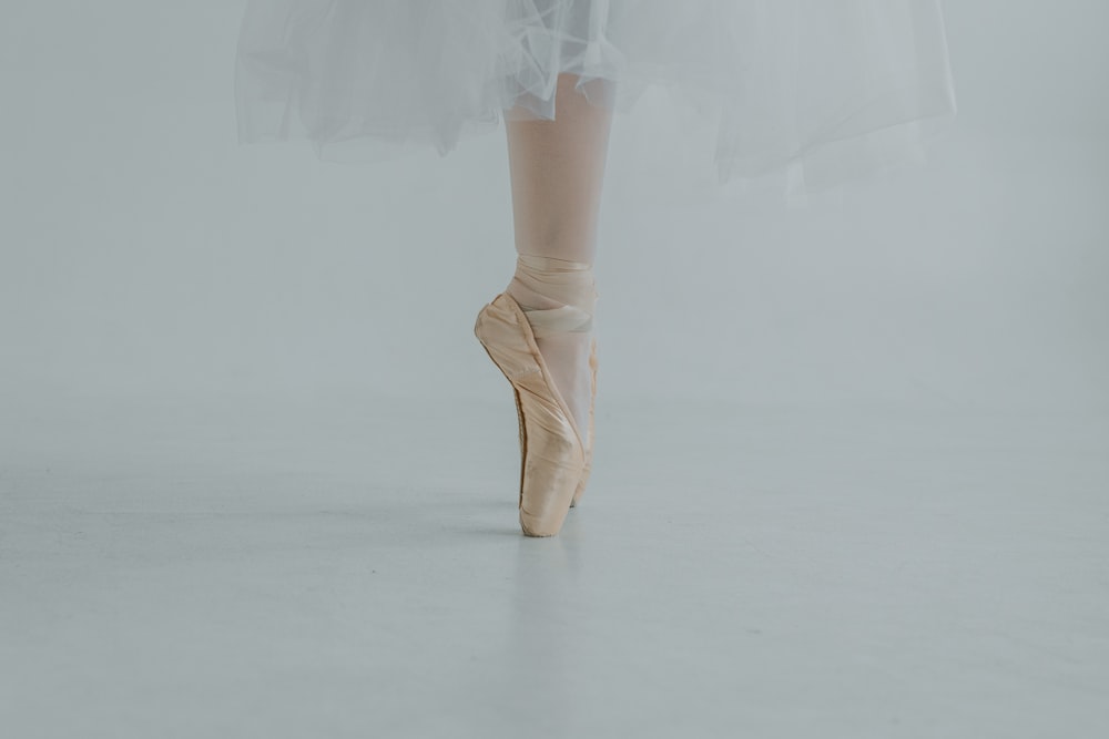 Una ballerina in tutù bianco e ballerine rosa