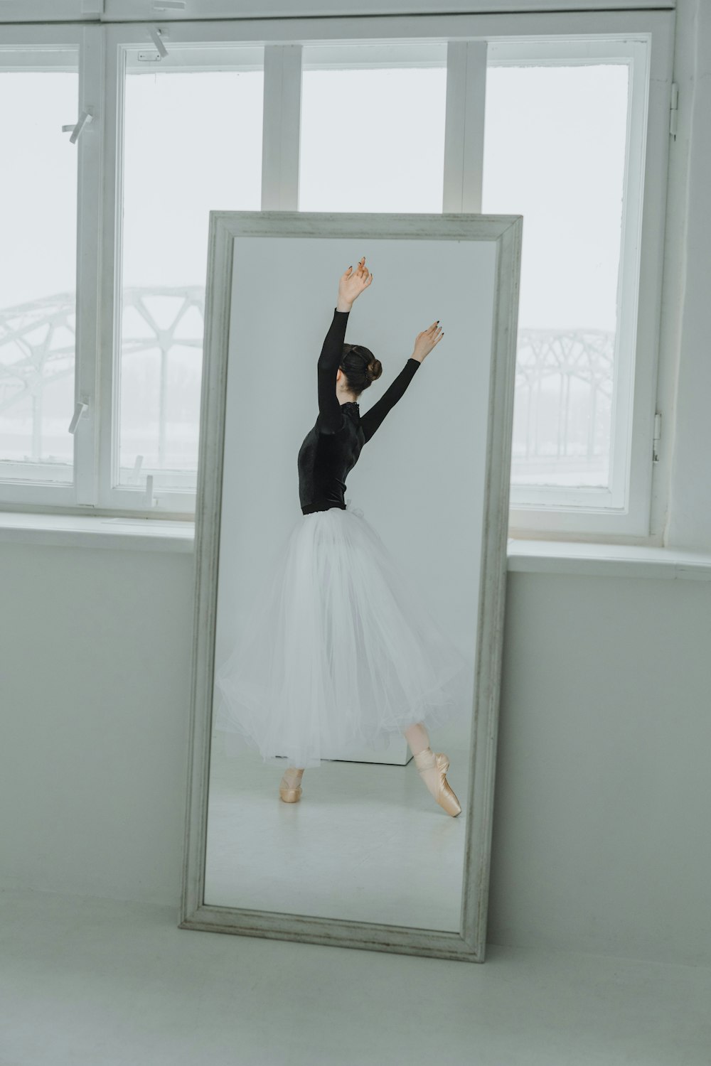 a ballerina in a tutu is reflected in a mirror