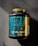 A large black container of ISO TOUCH pure isolate protein with a black and teal label, featuring bold text and nutritional information. The label includes details such as '100% Ultra-Filtrated', 'ISO PURE ISOLATE PROTEIN', and quantities of protein, BCAA, and glutamine. The container has a yellow cap and is placed on a dark textured surface with a striped pattern.