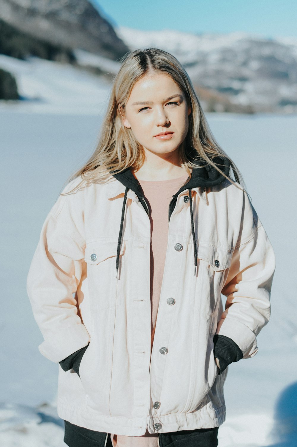 a woman standing in the snow wearing a jacket