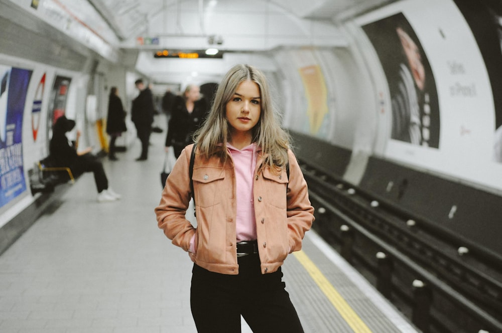 a woman standing in a subway station with her hands on her hips