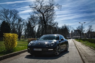 A sleek black car parked by a quiet street, ready to welcome a passenger for a smooth ride.