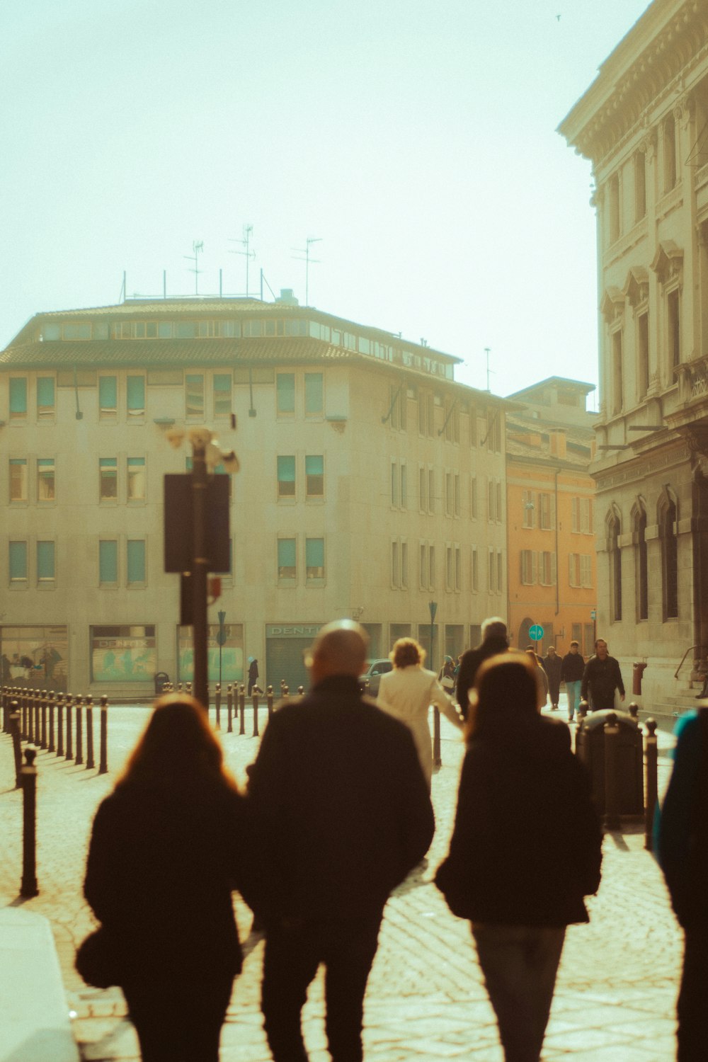 a group of people walking down a street next to tall buildings