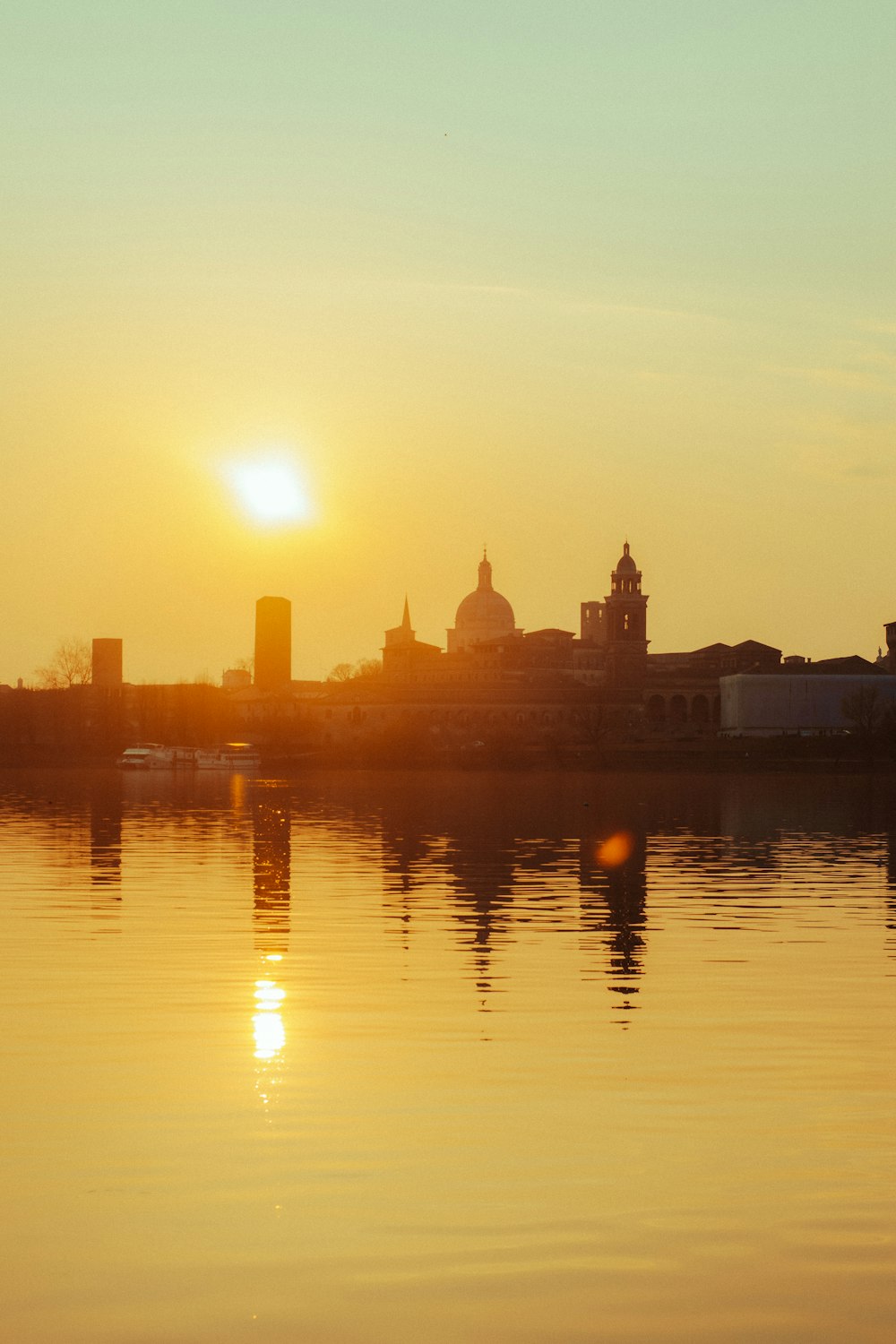 the sun is setting over a city on the water