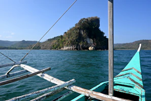 Close-up of a traditional outrigger boat’s colorful wooden hull bobbing gently near a secluded beach cove