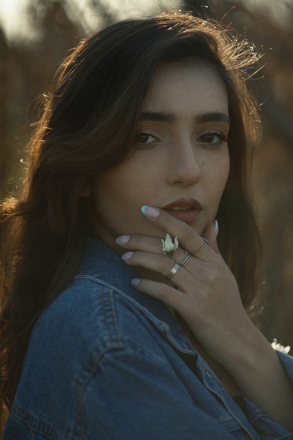 a woman in a denim jacket smoking a cigarette