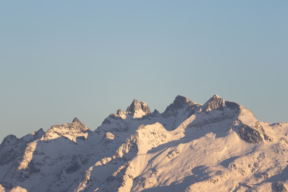 a large mountain covered in snow under a blue sky