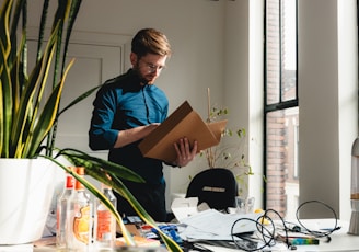 a man standing in an office holding a box