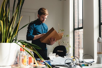 a man standing in an office holding a box