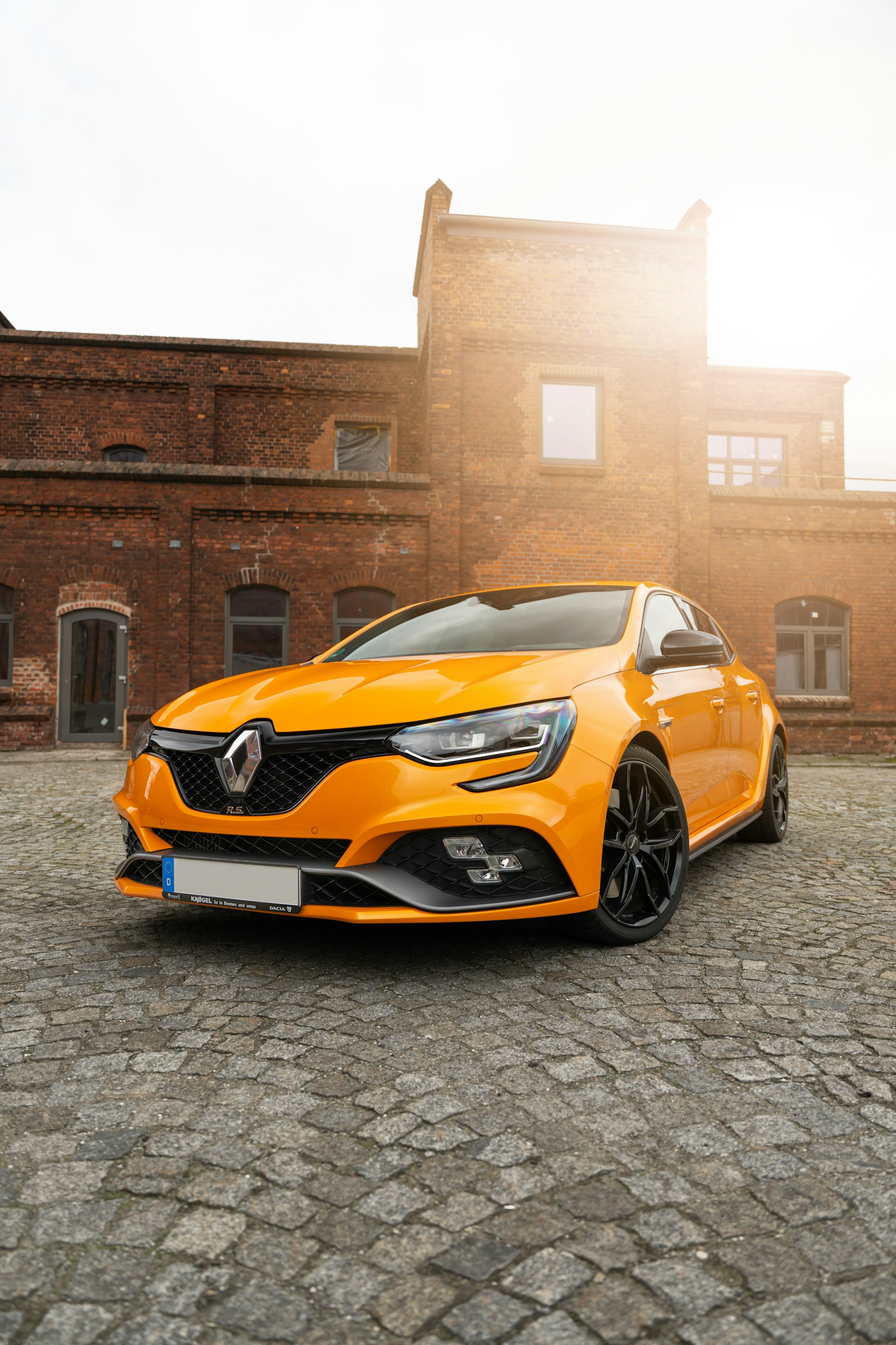 an orange car parked in front of a brick building