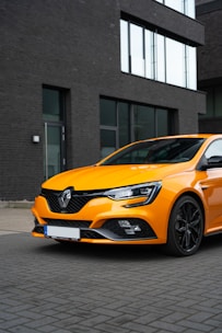 A sleek car rental scene with a modern vehicle parked in front of a hotel, highlighted by warm orange lighting.