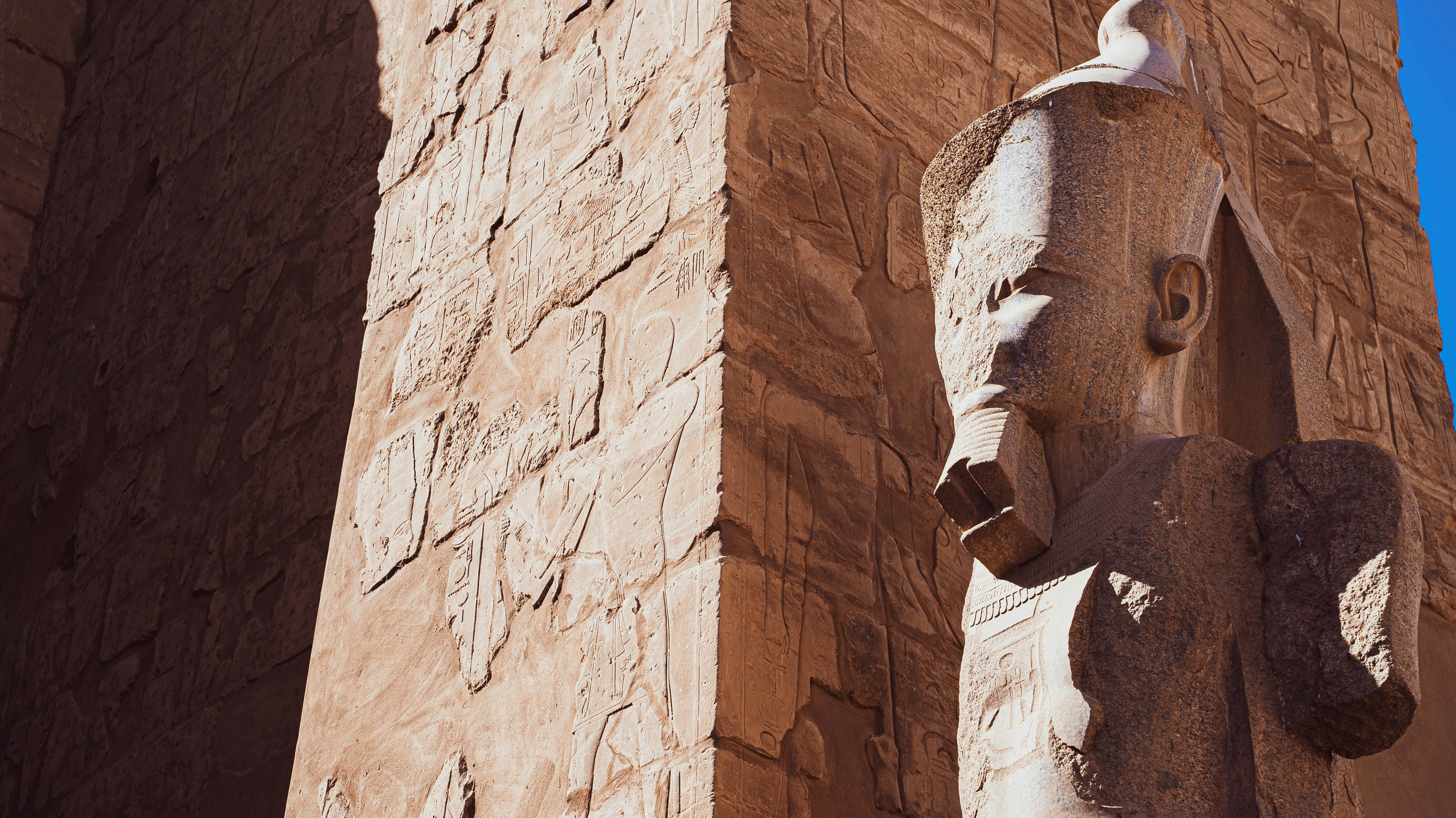 a tall building with a statue on the side of it, A decayed statue in the Karnak Temple Complex