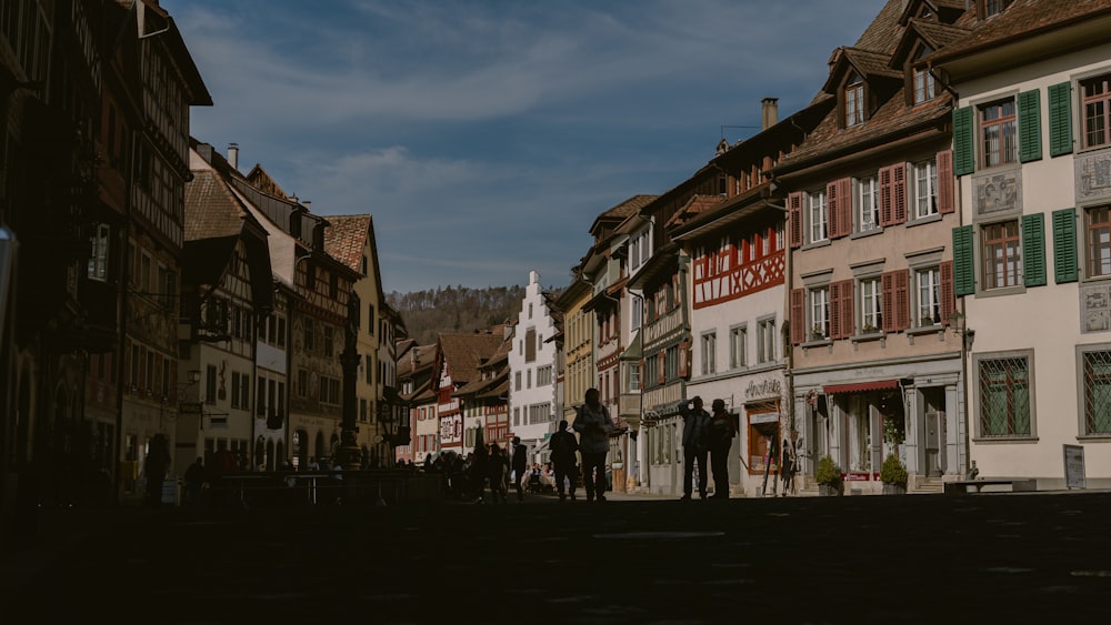 a group of people walking down a street next to tall buildings