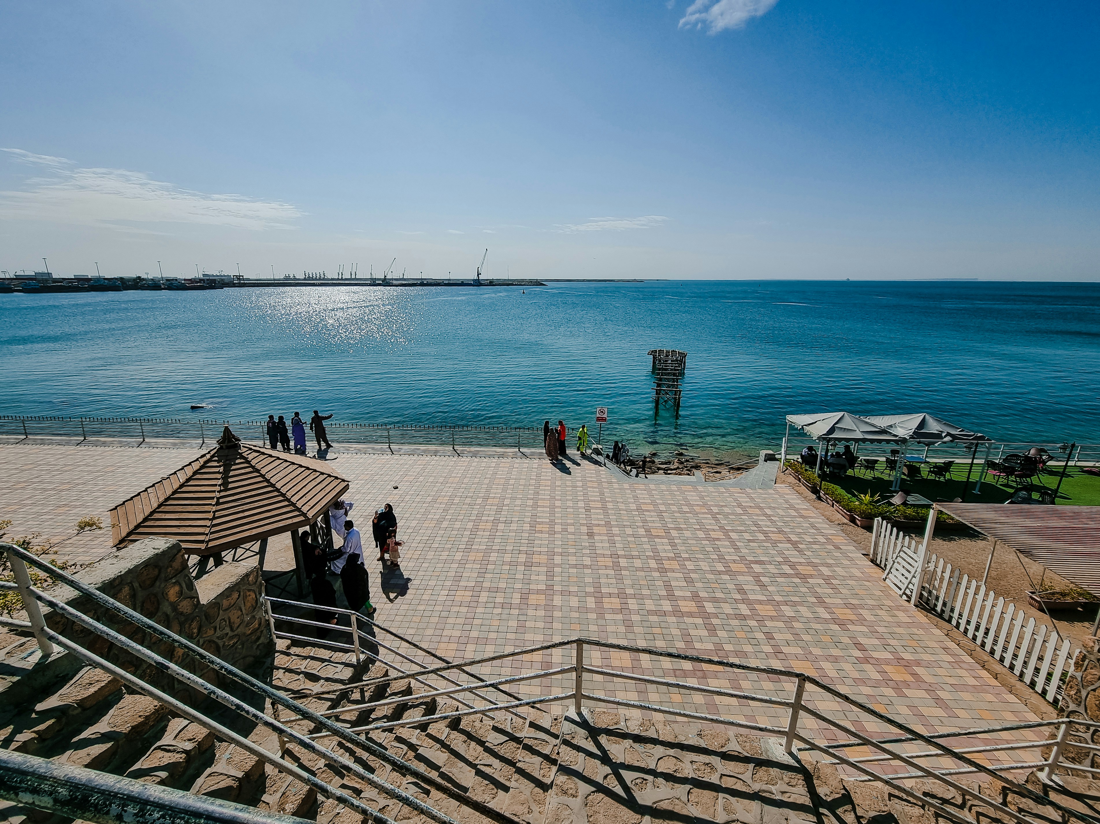 a group of people standing on top of a pier next to the ocean