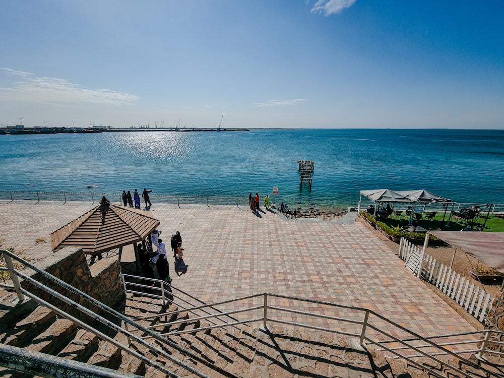 a group of people standing on top of a pier next to the ocean