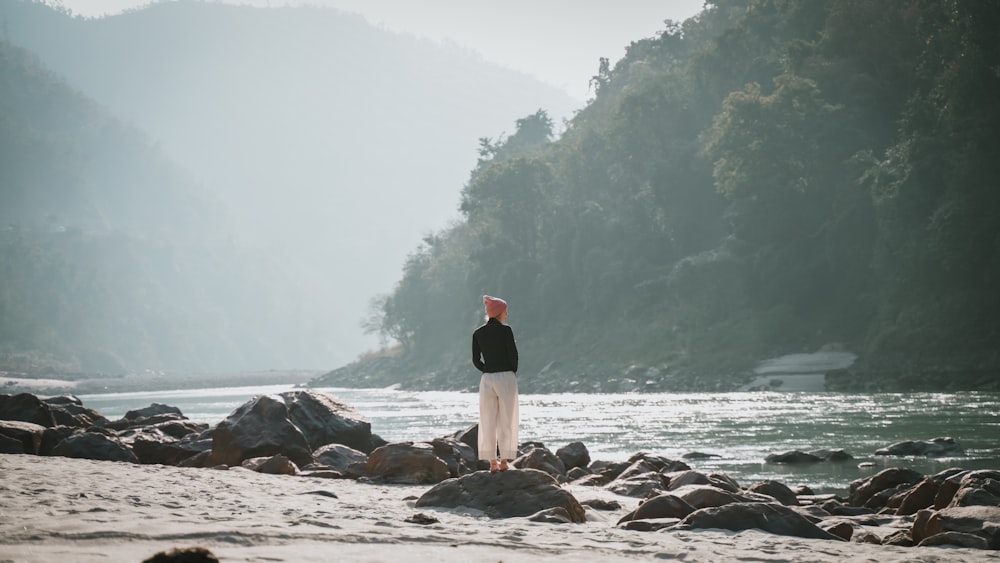 a man standing on a beach next to a body of water