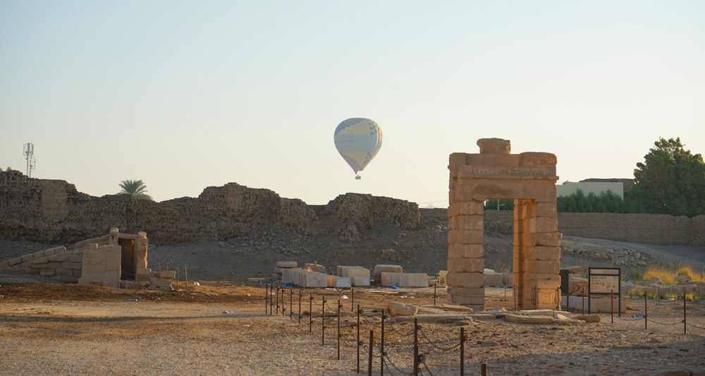 a hot air balloon flying over a stone structure