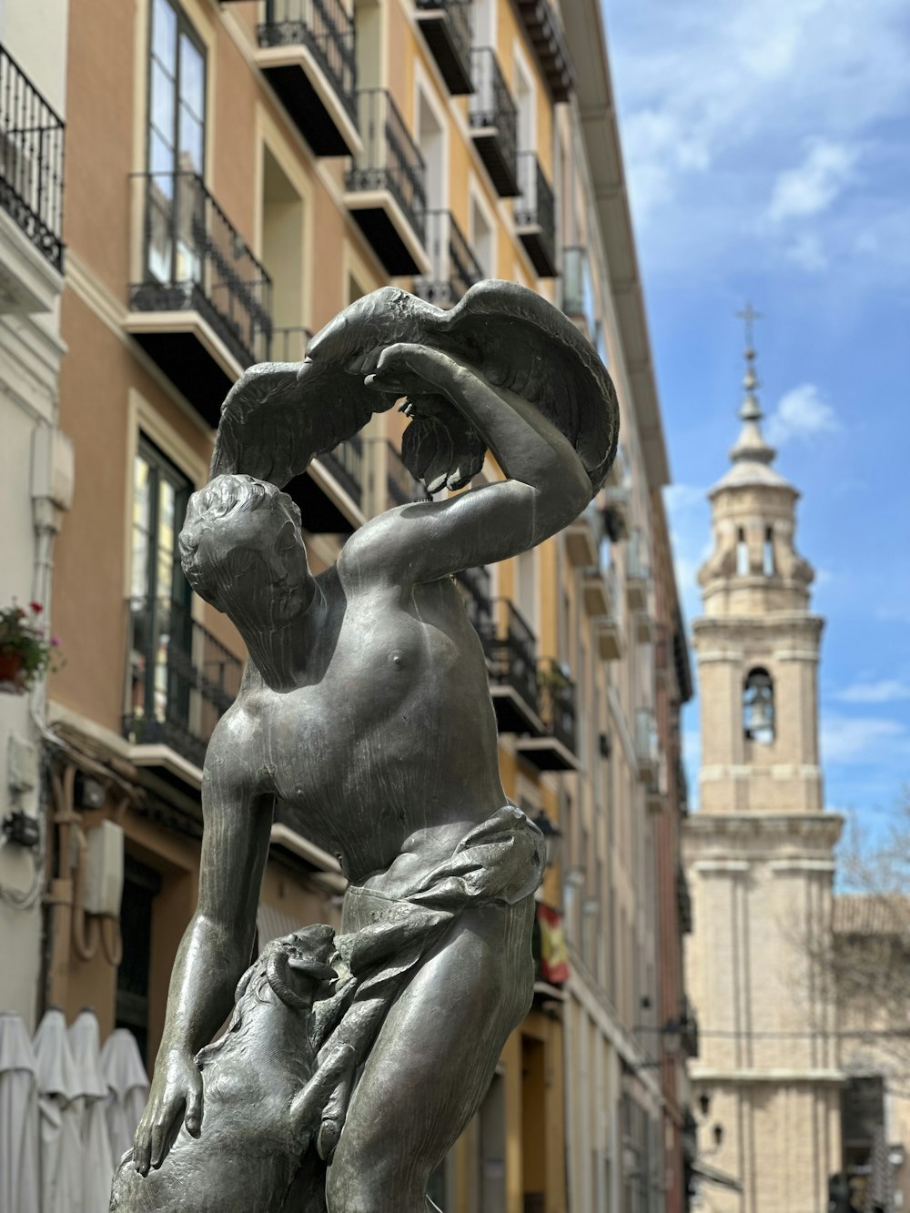 Una estatua de un hombre sosteniendo un sombrero frente a un edificio