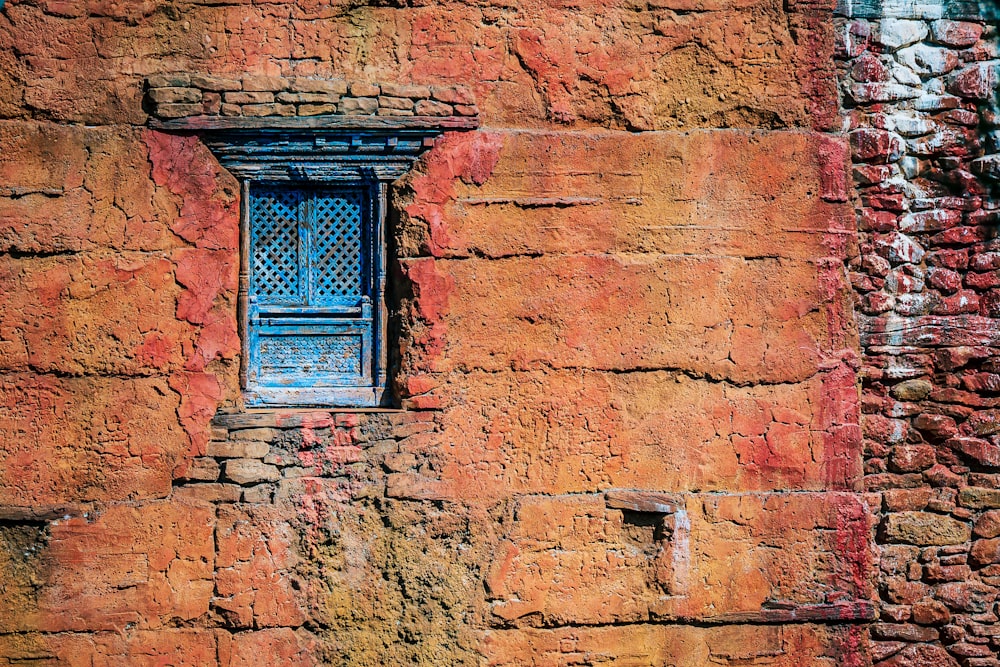 a blue window on the side of a brick building