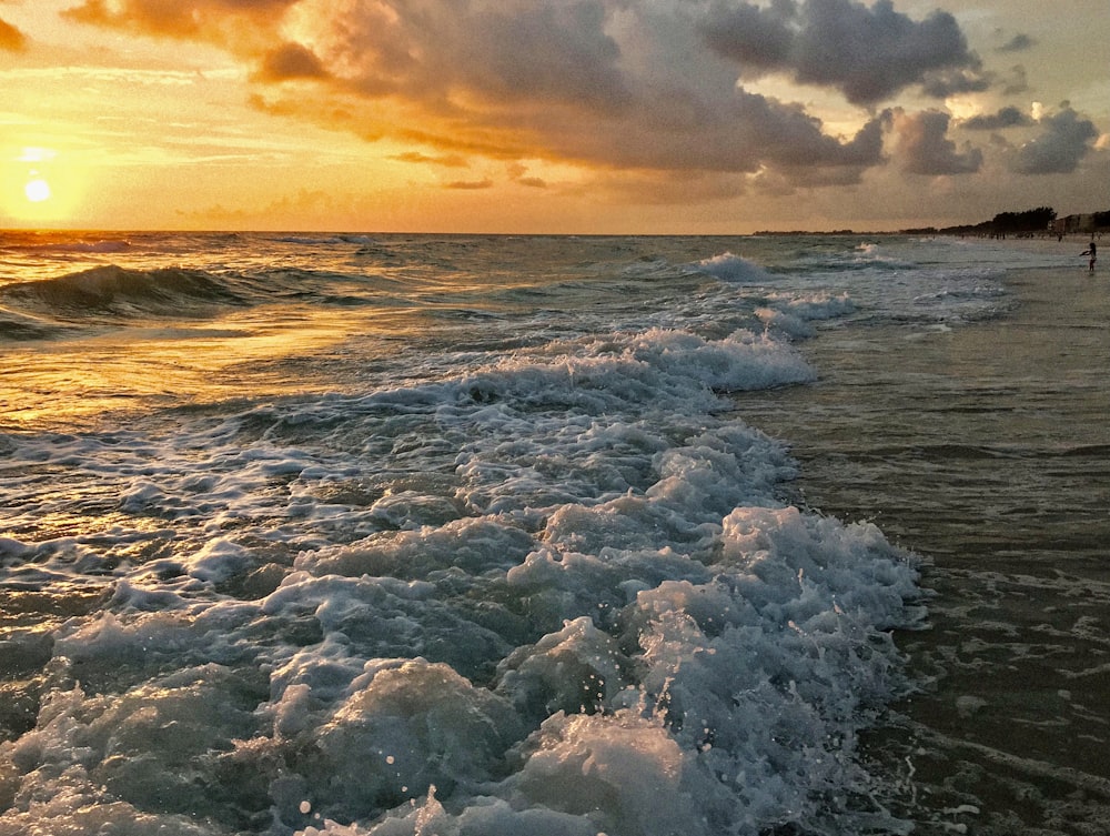 the sun is setting over the ocean with waves