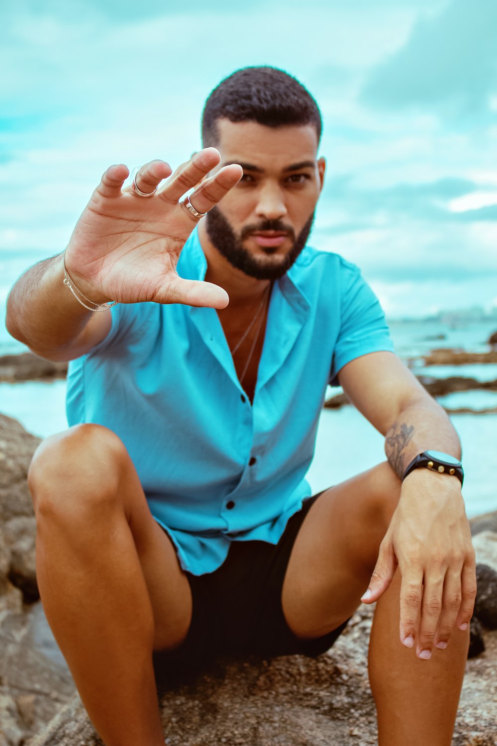 a man sitting on top of a rock next to a body of water