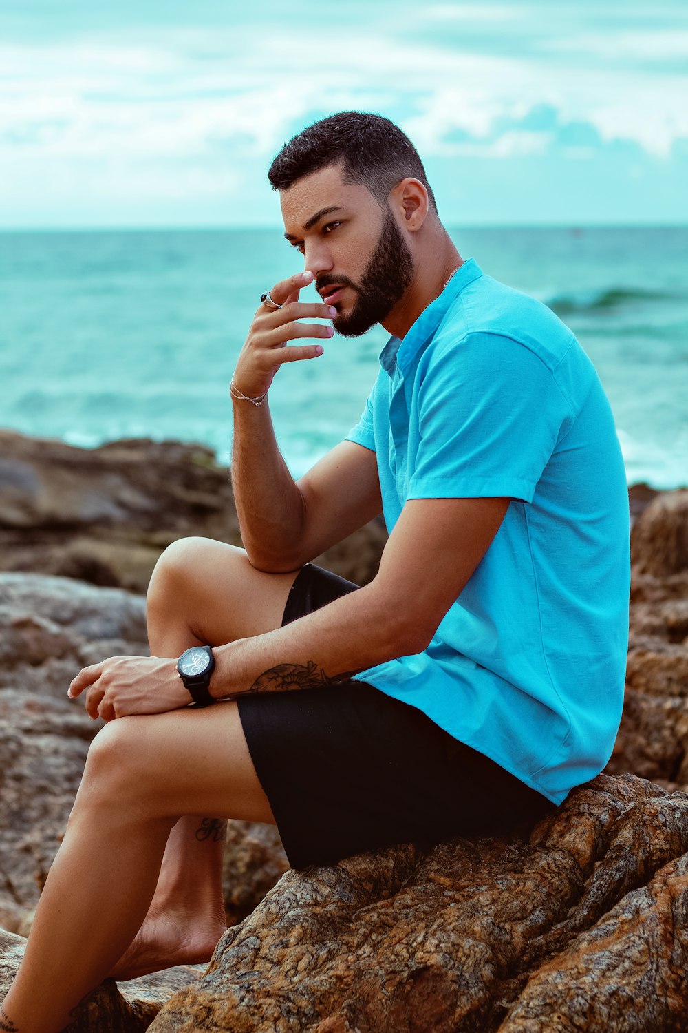 a man sitting on a rock next to the ocean