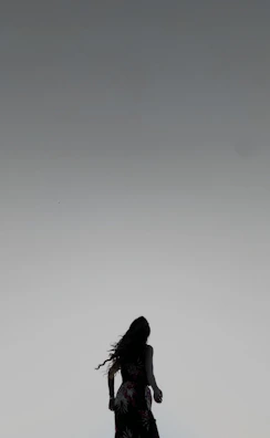 Minimalist line-art silhouette of a feminine figure in an elegant dress on a dusty rose gradient background.