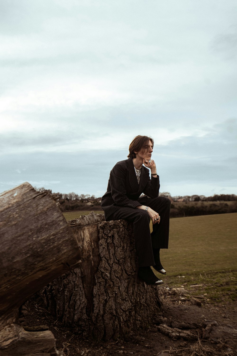 a man sitting on a tree stump talking on a cell phone